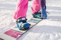 The girl in pink pants buttons fastening snowboard