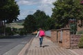 A girl with a pink satchel on her back runs down the street to school. The first day of school, the children are ready to study