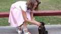 The girl in the pink skirt stroking black cat