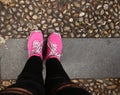 Girl in pink sneakers stands on a walkway in black jeans top view