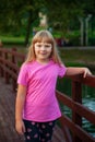 A girl in pink stands on the bridge.