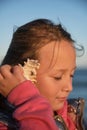 a girl listens to a seashell on the beach Royalty Free Stock Photo