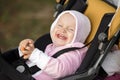 A girl in a pink suit sits in a yellow stroller and smiles, showing recently erupted teeth