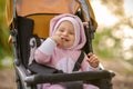 A girl in a pink suit sits in a yellow stroller and smiles, showing recently erupted teeth