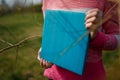 Girl in pink sweater holding photobook or photoalbum with leather turquoise cover and wooden texture
