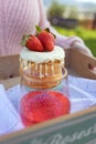 Girl with a pink sweater holding a wooden tray with strawberry sponge cake and red drink on it