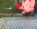 A girl in a pink sweater plays ping pong on an outdoor tennis table Royalty Free Stock Photo