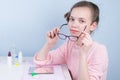 Girl in a pink sweater, sitting at the table, took off contact lenses and wears glasses to improve vision Royalty Free Stock Photo