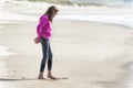 Girl in pink sweatshirt draws in sand with toe