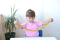 Girl in pink t-shirt hold and stretching yellow slime with golden braids on a white table. child playing with a slime toy. Making