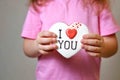 Girl in a pink t-shirt holds a gingerbread valentine card. gift for valentine`s day. congratulations