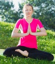 Girl in pink T-shirt is sitting and doing meditation