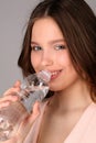 Girl in pink top drinking water. Close up. Gray background Royalty Free Stock Photo