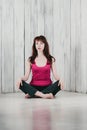 A girl in a pink top, sitting cross-legged on the floor, light b Royalty Free Stock Photo