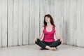 A girl in a pink top, sitting cross-legged on the floor, smiling Royalty Free Stock Photo