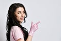 Girl in pink uniform and disposable gloves standing sideways, isolated on white. She smiling, pointing at something. Close up Royalty Free Stock Photo