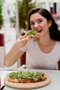 Girl with pinsa romana in cafe on summer terrace. Young woman eating pinsa and drinking wine