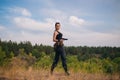 Girl with a pistol in nature. Against the background of yellow grass. The female army on the hunt