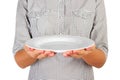 Girl in the plaid shirt is holding an empty round white plate in front of her. woman hand hold empty dish for you desing. perspect Royalty Free Stock Photo