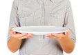 Girl in the plaid shirt is holding an empty round white plate in front of her. woman hand hold empty dish for you desing. perspect Royalty Free Stock Photo