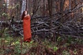 Girl in plaid stands near downed trees in forest