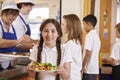 Girl with plaits holding plate of food in school cafeteria