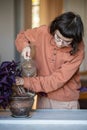 Girl plant lover pouring watering houseplants Oxalis with purple leaves at home.