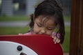 Girl in the playground. The smile of a child. Asian appearance. A preschool girl plays hide and seek in the yard.