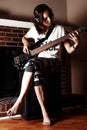 Girl playing Bass guitar indoor in dark room Royalty Free Stock Photo