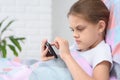 Girl playing on a cell phone while lying in bed Royalty Free Stock Photo