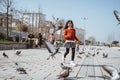 girl playing and chasing pigeons in city square Royalty Free Stock Photo