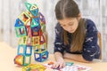 Girl playing colorful magnet plastic blocks kit at indoor playground. girl made a toy robot. The child playing educational games. Royalty Free Stock Photo