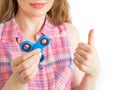 Girl playing with a colourful hand fidget spinner toy and showing thumbs up Royalty Free Stock Photo