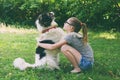 Girl playing with dog on grass. Teenager hugging Carpathian Shepherd Dog in the summer park. Friendship concept of man and animal Royalty Free Stock Photo