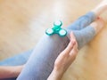 Girl playing with a glossy light colourful hand fidget spinner toy Royalty Free Stock Photo