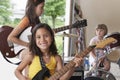 Girl Playing Guitar With Band In Garage Royalty Free Stock Photo