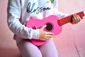 Girl playing the guitar , retro pink wooden guitar in small hands