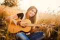 Girl playing the guitar in a wheat field Royalty Free Stock Photo