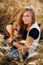 Girl playing the guitar in a wheat field Royalty Free Stock Photo