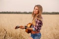 Girl playing the guitar in a wheat field Royalty Free Stock Photo