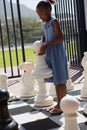 Girl playing large chess on sunny day