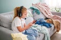 A girl is playing on a mobile phone. The room is a mess. The child scattered things in the room Royalty Free Stock Photo