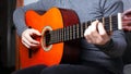 Girl playing an orange acoustic guitar grips the chord on the fretboard. musical instrument lesson close-up Royalty Free Stock Photo