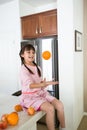 Girl playing with oranges in kitchen Royalty Free Stock Photo