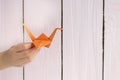 A girl is playing with an origami crane made of paper that she made herself. On a wooden background Royalty Free Stock Photo