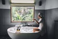 Girl playing with soap foam on bath by window