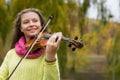 Girl playing the violin in the autumn park at a autumn foliage b Royalty Free Stock Photo