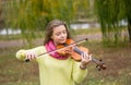 Girl playing the violin eyes closed in the autumn park at a lake Royalty Free Stock Photo