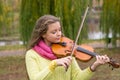 Girl playing the violin eyes closed in the autumn park at a lake Royalty Free Stock Photo