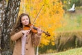 Girl playing the violin and smiling in the autumn park at a lake Royalty Free Stock Photo